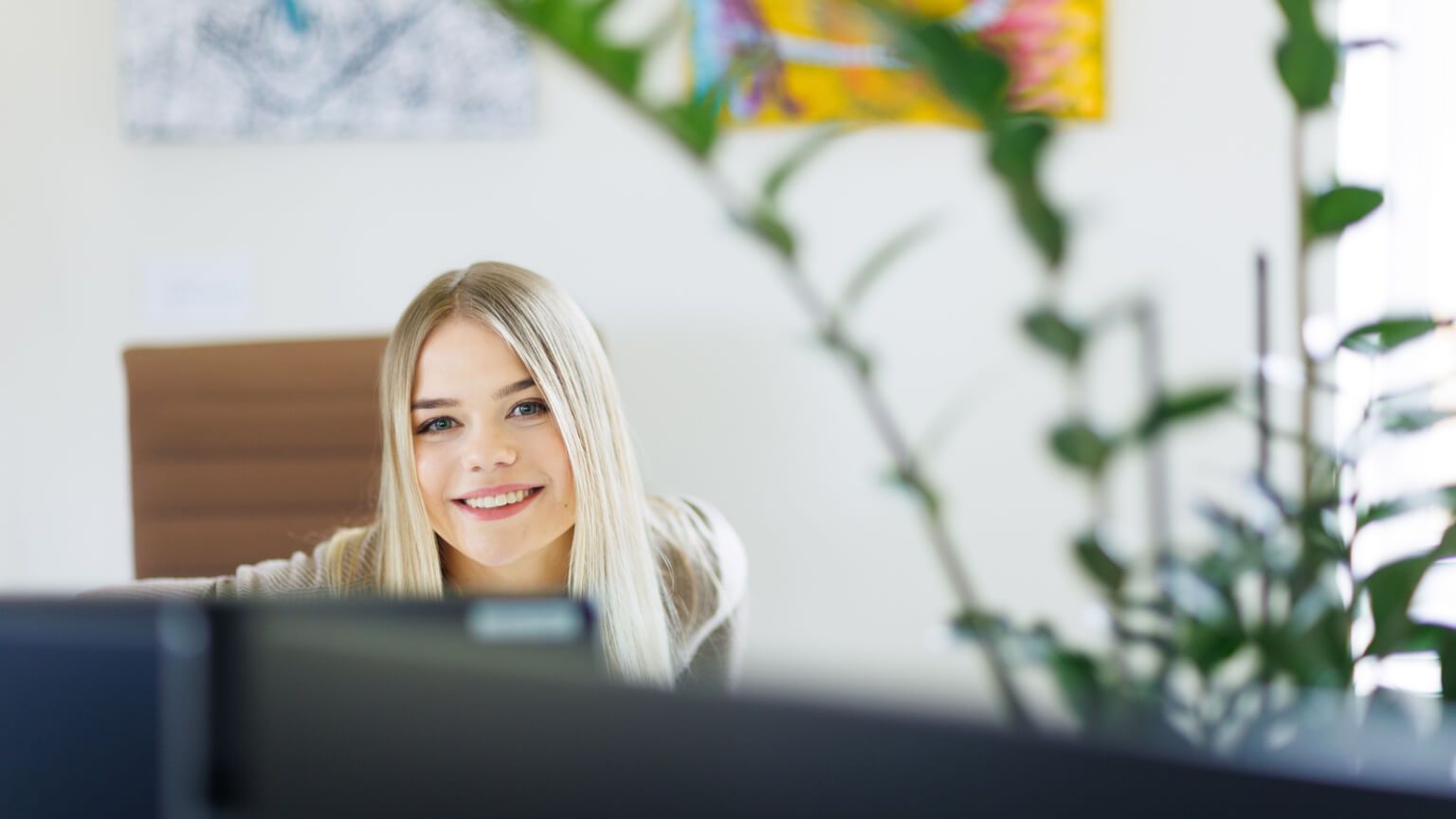 woman smiling from behind a computer